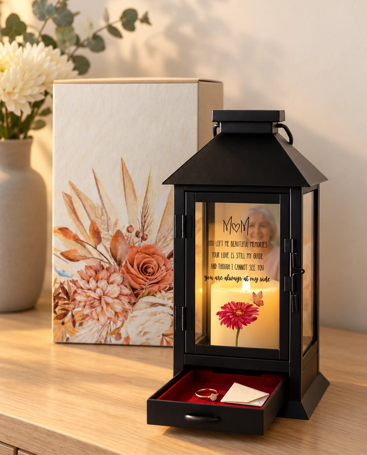 The black metal lantern, lit, its drawer open and a photograph behind the glass, beside its gift box