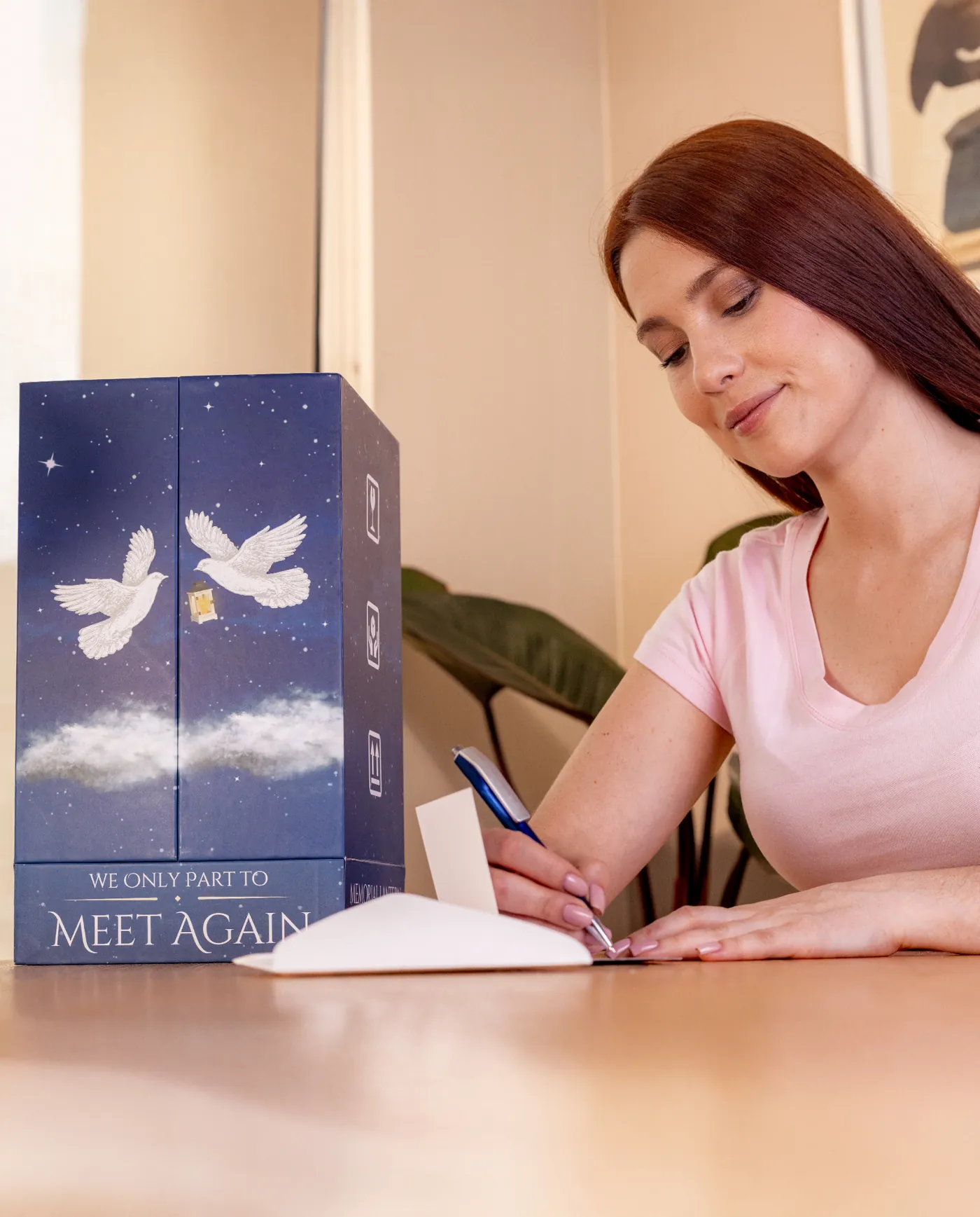 A woman writing a card beside a STILLWIND gift box